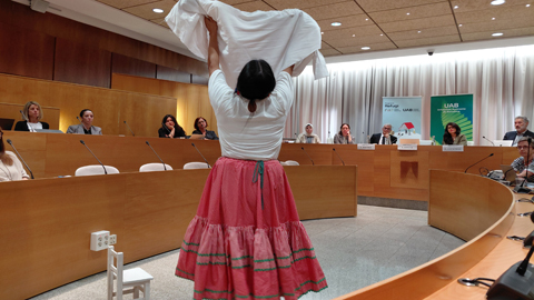 Sala d'actes amb estudiant refugiada ballant.